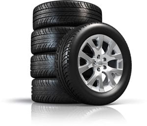 Stapel autobanden met een velg, klaar voor montage bij Garage Popelier.