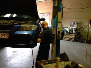 Monteur werkt onder de motorkap van een wagen op de brug.